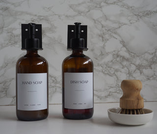 Two brown bottles labeled 'Hand Soap' and 'Dish Soap' on a marble countertop.