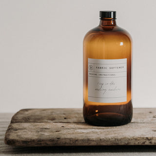 Amber bottle of fabric softener on a wooden surface with a neutral background