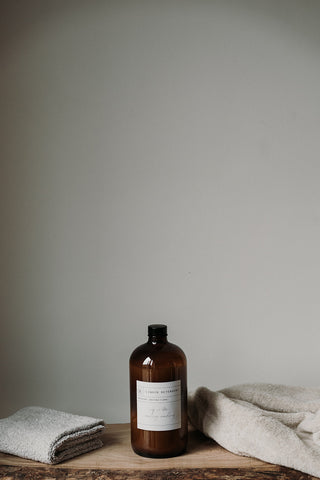 Amber bottle of liquid detergent on a wooden surface with a neutral background