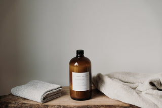Amber bottle of fabric softener on a wooden surface with a neutral background