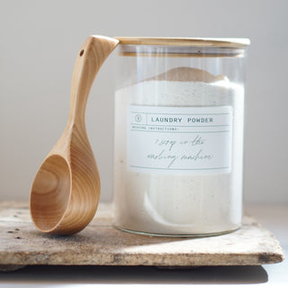 wide mouth bamboo lid with a scoop, with laundry powder inside.