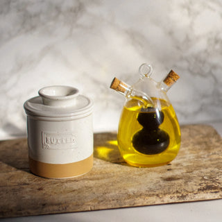 Butter container and glass bottle with oil on a wooden surface