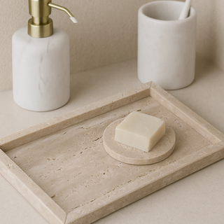 Bathroom counter with marble soap dish, soap, and ceramic cup on a travertine tray