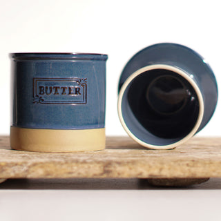 Blue ceramic butter container with gold base on a wooden surface
