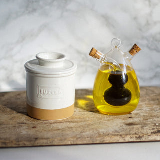 Butter container and glass bottle with oil on a wooden surface