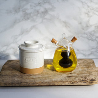 Butter container and glass bottle with oil on a wooden surface