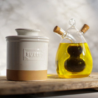 Butter container and glass bottle with oil on a wooden surface