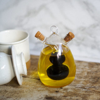 Glass bottle with cork stoppers containing a yellow liquid on a wooden surface.