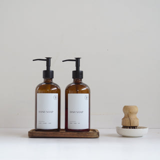 Two brown bottles with pump dispensers on a white surface against a light gray background