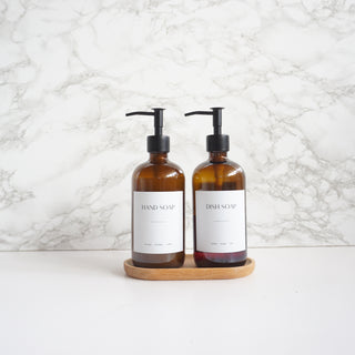 Two brown soap bottles with pump dispensers on a white surface and marble wall background.