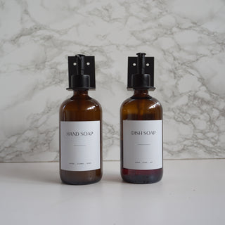Two brown soap bottles with black nozzles on a marble background