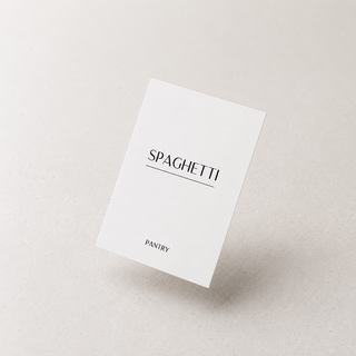 A minimalist white card or packaging insert with the word 'SPAGHETTI' in black serif text and 'PANTRY' near the bottom, photographed on a light warm gray background.