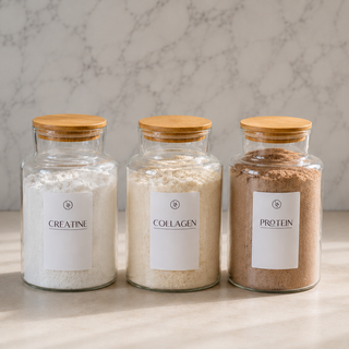 Three glass jars labeled 'Creatine', 'Collagen', and 'Protein' on a marble surface.